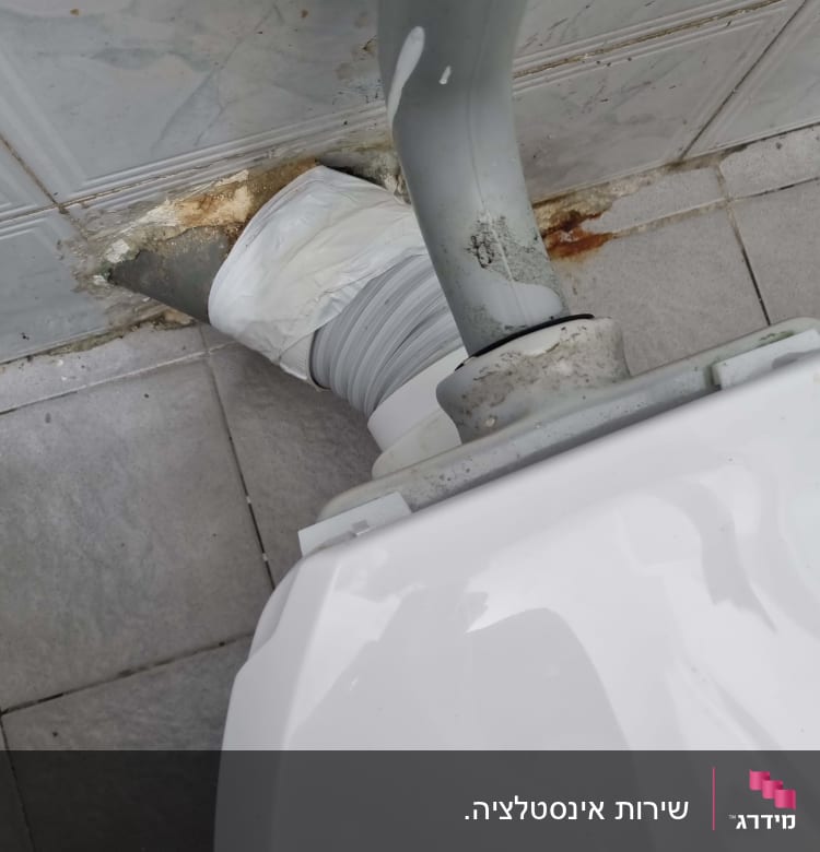 צינור אפור מחובר לאסלה עם חיבור לבן